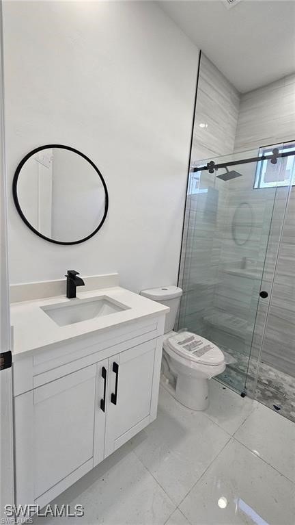 bathroom with vanity, a shower with door, and toilet