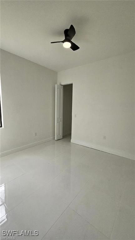 empty room featuring ceiling fan and baseboards