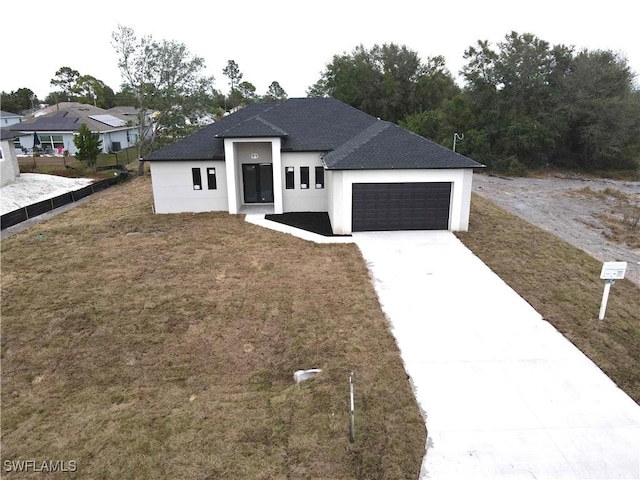 view of front facade with a garage, a shingled roof, concrete driveway, a front yard, and stucco siding