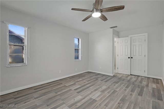 spare room with ceiling fan, plenty of natural light, and light wood-type flooring