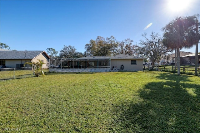 back of house with glass enclosure and a lawn