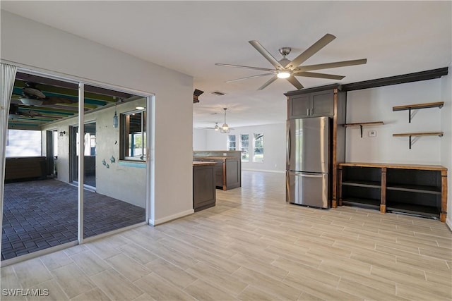 interior space with stainless steel refrigerator, dark brown cabinets, ceiling fan, and hanging light fixtures