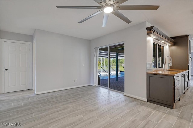 unfurnished living room featuring ceiling fan and sink