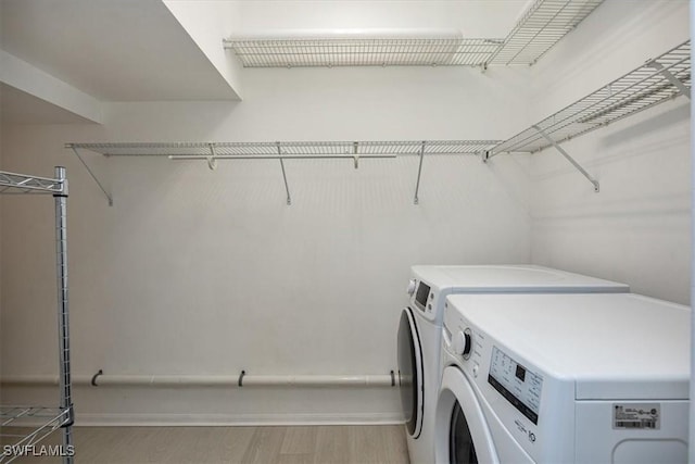 laundry area featuring washing machine and clothes dryer and light wood-type flooring