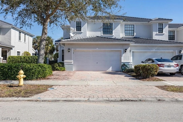 view of front of house featuring a garage, decorative driveway, a tile roof, and stucco siding