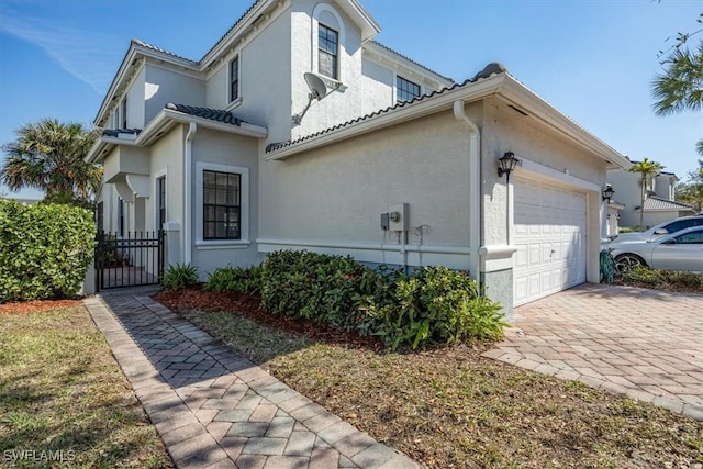 view of property exterior featuring decorative driveway, an attached garage, and stucco siding