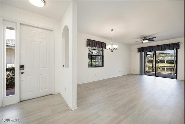 entrance foyer with ceiling fan with notable chandelier, light wood-type flooring, and a wealth of natural light