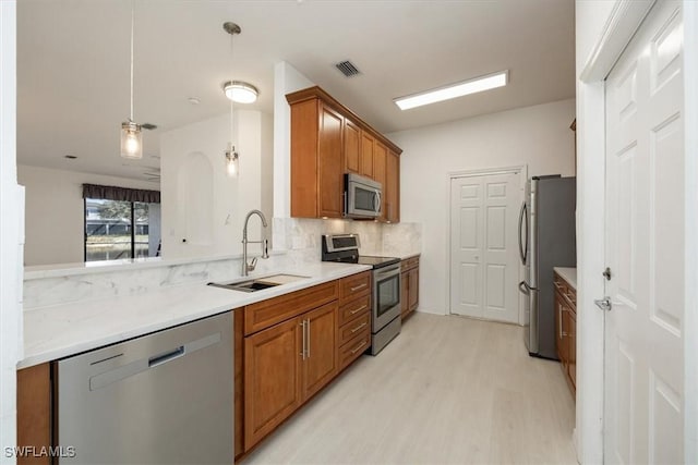 kitchen with sink, backsplash, hanging light fixtures, stainless steel appliances, and light wood-type flooring