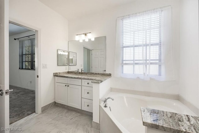 bathroom featuring marble finish floor, vanity, and a bath