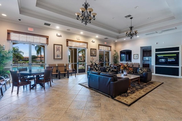 living room featuring a notable chandelier, a tray ceiling, and french doors