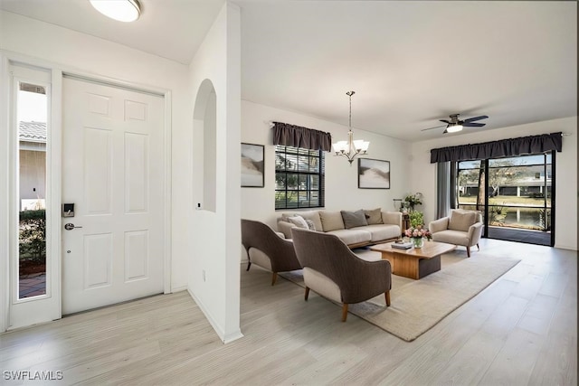 foyer with light wood-style floors, plenty of natural light, arched walkways, and a notable chandelier