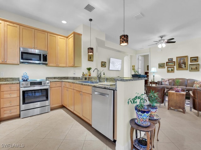 kitchen with stainless steel appliances, light tile patterned flooring, decorative light fixtures, kitchen peninsula, and light brown cabinets