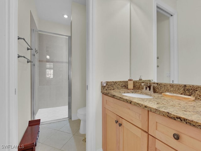 bathroom with tile patterned flooring, vanity, a shower with door, and toilet