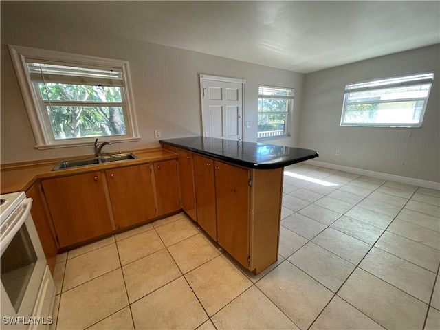 kitchen with electric stove, kitchen peninsula, sink, and light tile patterned floors