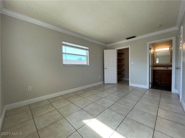 unfurnished bedroom featuring light tile patterned floors, crown molding, a walk in closet, and a closet