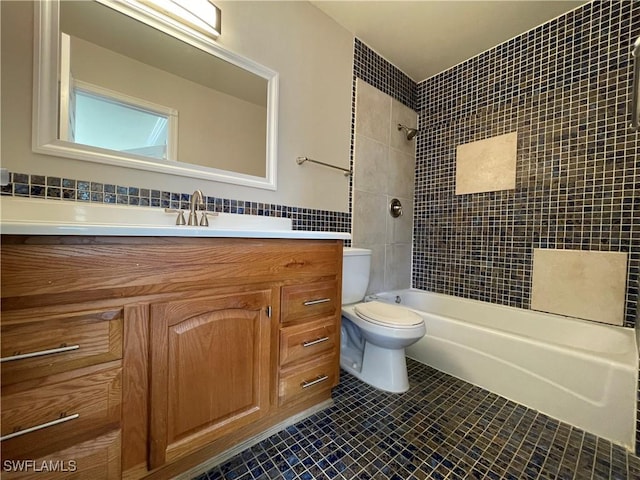 full bathroom featuring tile patterned floors, toilet, tile walls, vanity, and tiled shower / bath combo