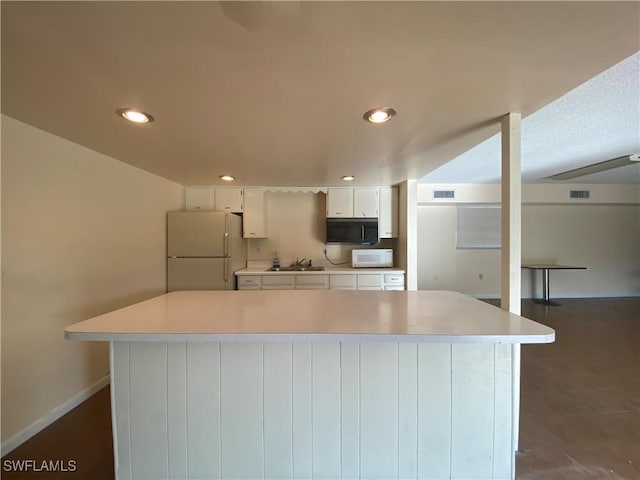 kitchen featuring white cabinetry, a kitchen island, sink, and white appliances