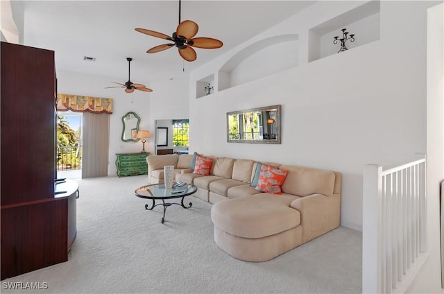 carpeted living room with ceiling fan and a high ceiling