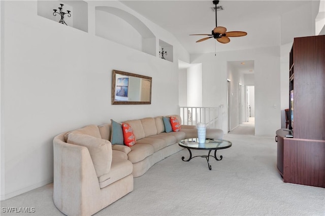 carpeted living room featuring a towering ceiling and ceiling fan