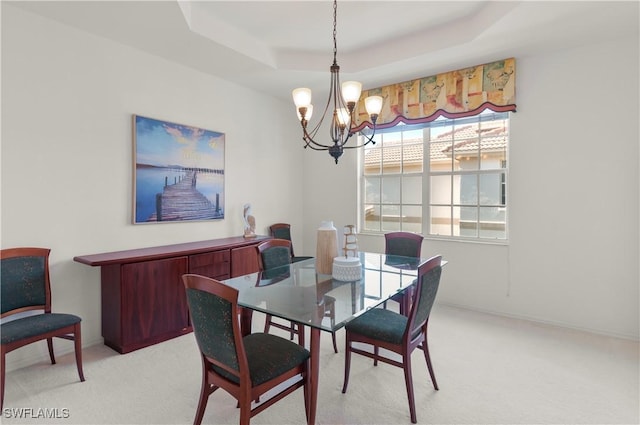 dining space with a raised ceiling, light colored carpet, and an inviting chandelier