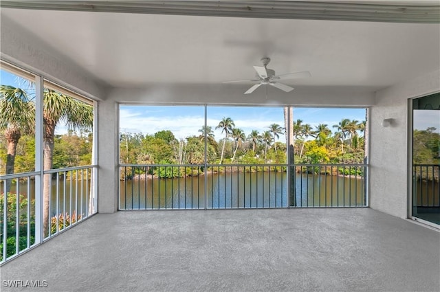 unfurnished sunroom featuring ceiling fan and a water view