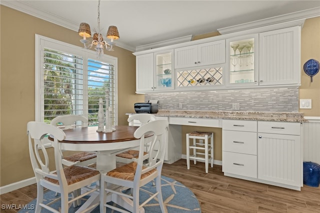 dining space featuring crown molding, a chandelier, built in desk, and light hardwood / wood-style floors