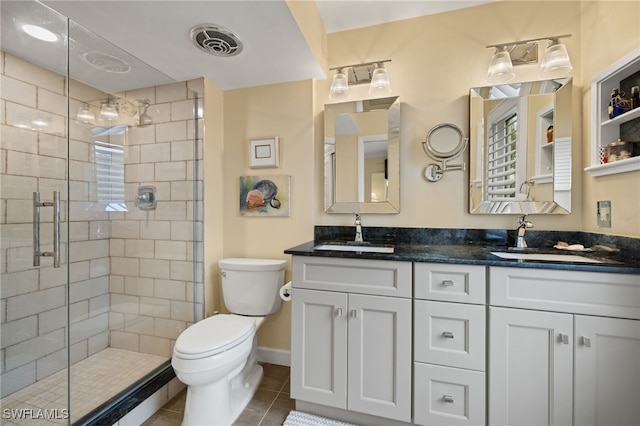 bathroom featuring tile patterned flooring, vanity, toilet, and walk in shower