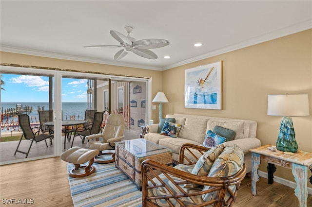 living room with crown molding, a water view, ceiling fan, and light hardwood / wood-style floors