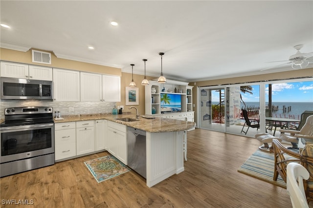 kitchen featuring sink, white cabinets, hanging light fixtures, kitchen peninsula, and stainless steel appliances