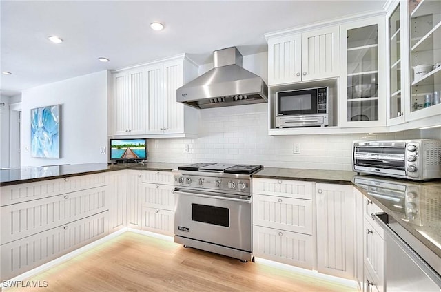 kitchen featuring white cabinetry, appliances with stainless steel finishes, light wood-type flooring, and wall chimney range hood