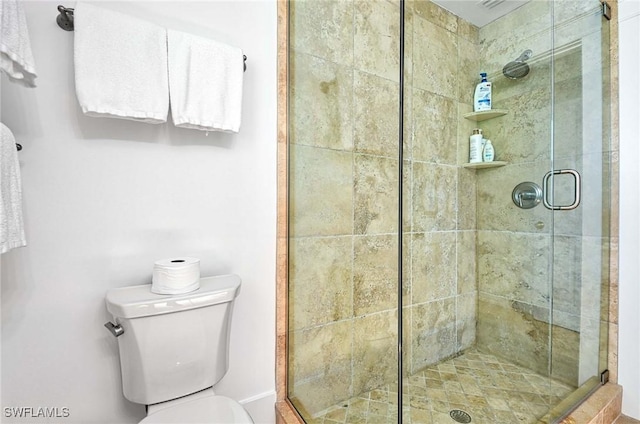 bathroom with a shower with shower door and toilet