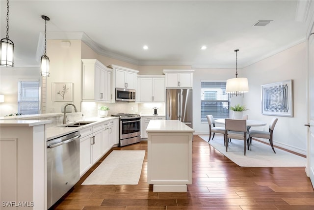 kitchen featuring pendant lighting, appliances with stainless steel finishes, kitchen peninsula, and sink