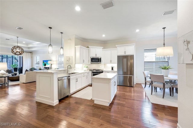 kitchen featuring sink, stainless steel appliances, dark hardwood / wood-style floors, decorative light fixtures, and kitchen peninsula