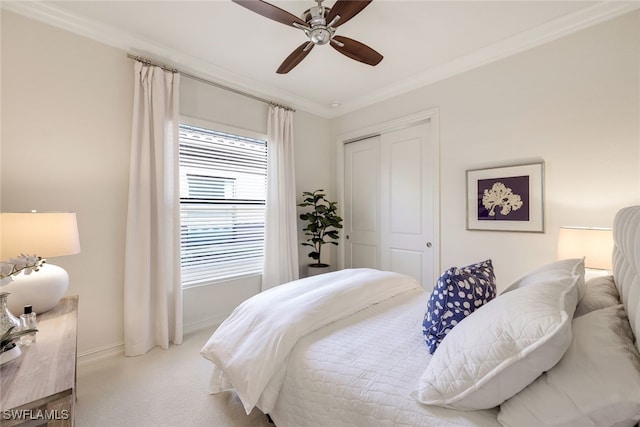 bedroom featuring crown molding, light colored carpet, ceiling fan, and a closet