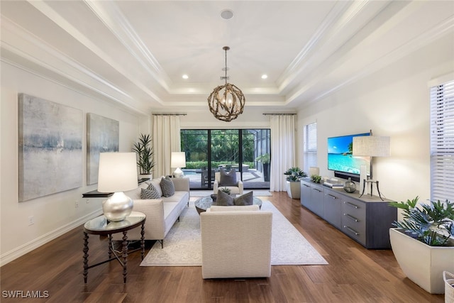 living room with dark wood-type flooring, ornamental molding, a raised ceiling, and a chandelier