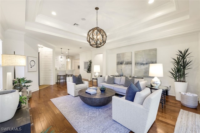 living room featuring dark hardwood / wood-style floors, a tray ceiling, and a chandelier