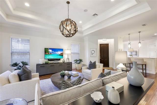 living room featuring ornamental molding, light hardwood / wood-style flooring, and a tray ceiling