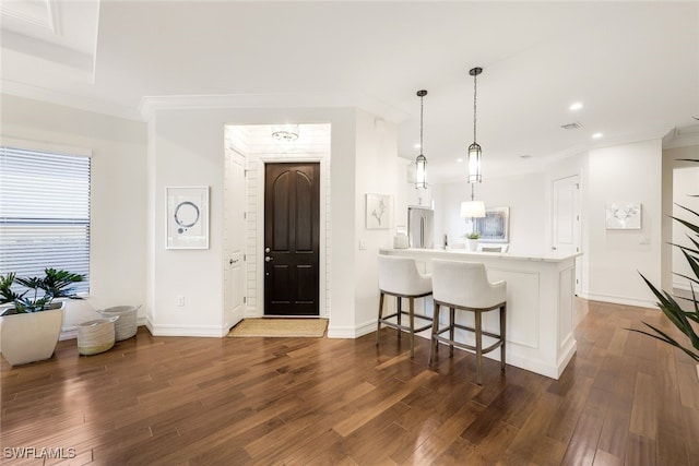 kitchen featuring stainless steel refrigerator, a breakfast bar area, hanging light fixtures, kitchen peninsula, and dark wood-type flooring