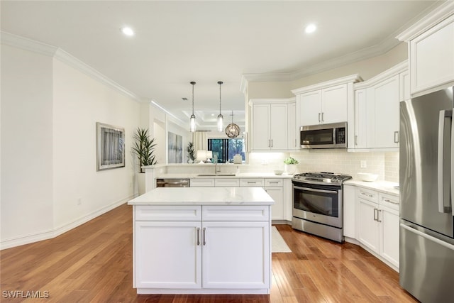 kitchen featuring pendant lighting, crown molding, white cabinetry, stainless steel appliances, and kitchen peninsula