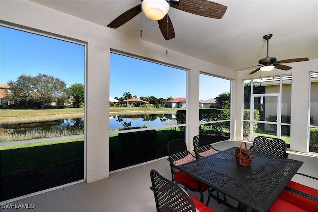 sunroom featuring a water view and ceiling fan