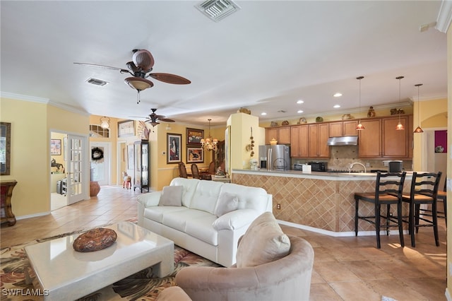 living room with ornamental molding, ceiling fan with notable chandelier, and light tile patterned floors