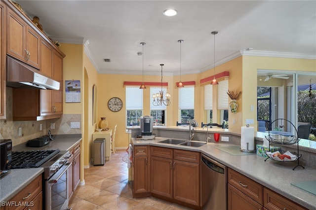 kitchen with appliances with stainless steel finishes, pendant lighting, tasteful backsplash, sink, and crown molding