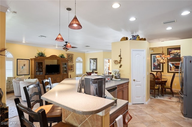 kitchen with a breakfast bar, hanging light fixtures, ornamental molding, appliances with stainless steel finishes, and kitchen peninsula