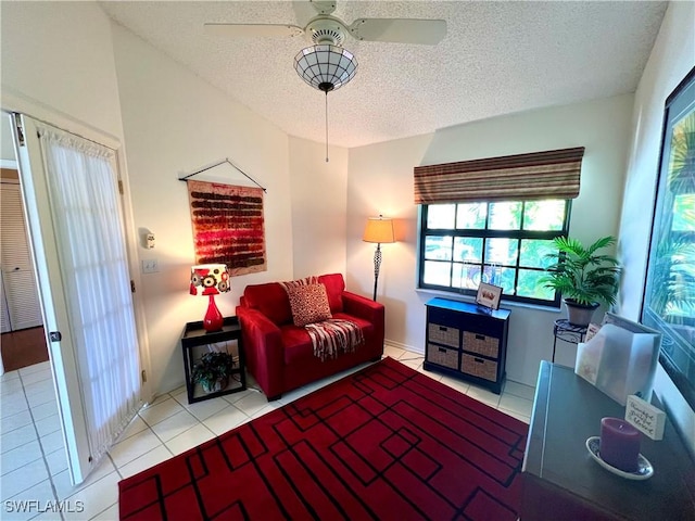 living room featuring light tile patterned flooring, ceiling fan, and a textured ceiling