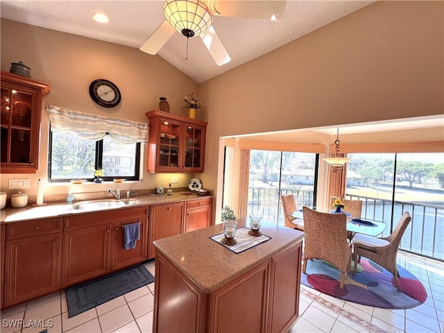 kitchen with vaulted ceiling, sink, a center island, ceiling fan, and a healthy amount of sunlight