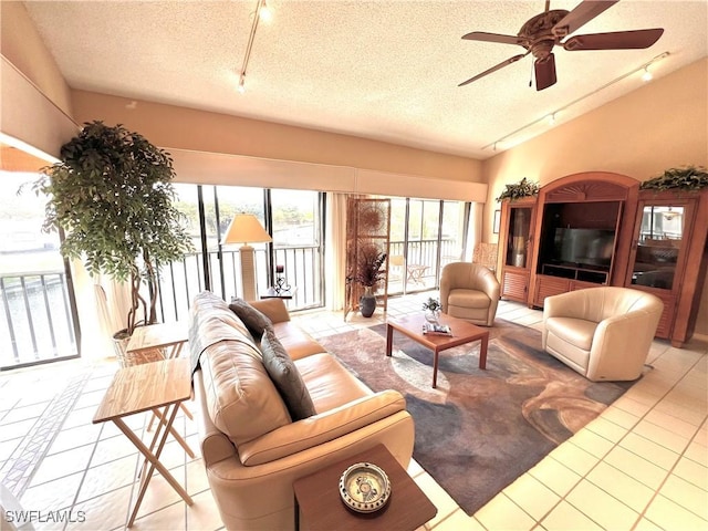 tiled living room featuring vaulted ceiling, rail lighting, ceiling fan, and a textured ceiling