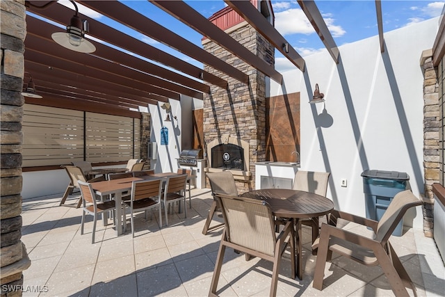 view of patio featuring area for grilling, an outdoor stone fireplace, and a pergola