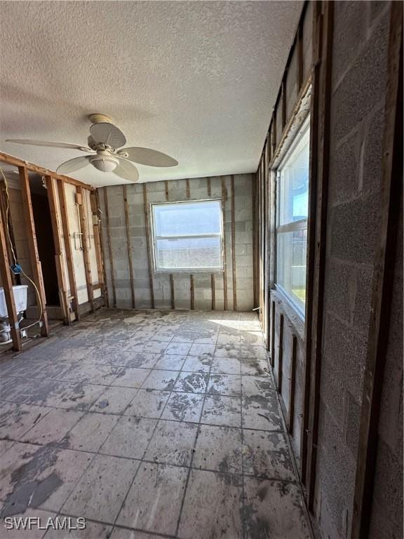 miscellaneous room with ceiling fan and a textured ceiling