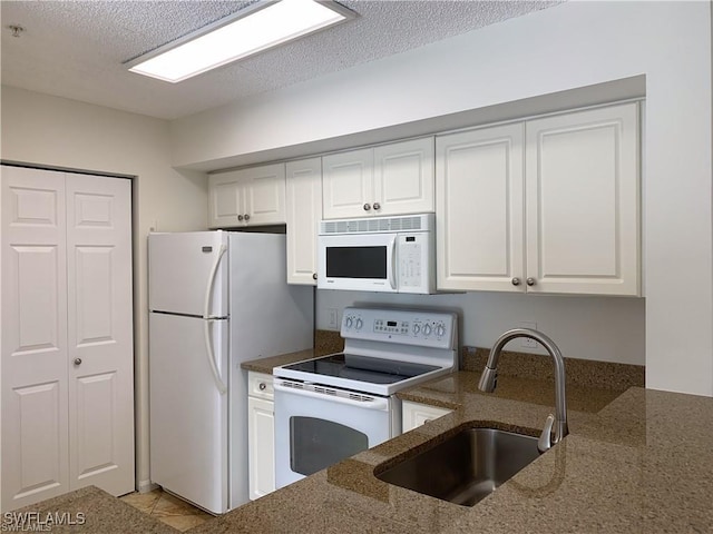 kitchen featuring sink, white cabinets, white appliances, and dark stone counters