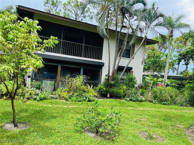 rear view of property featuring a yard and stucco siding